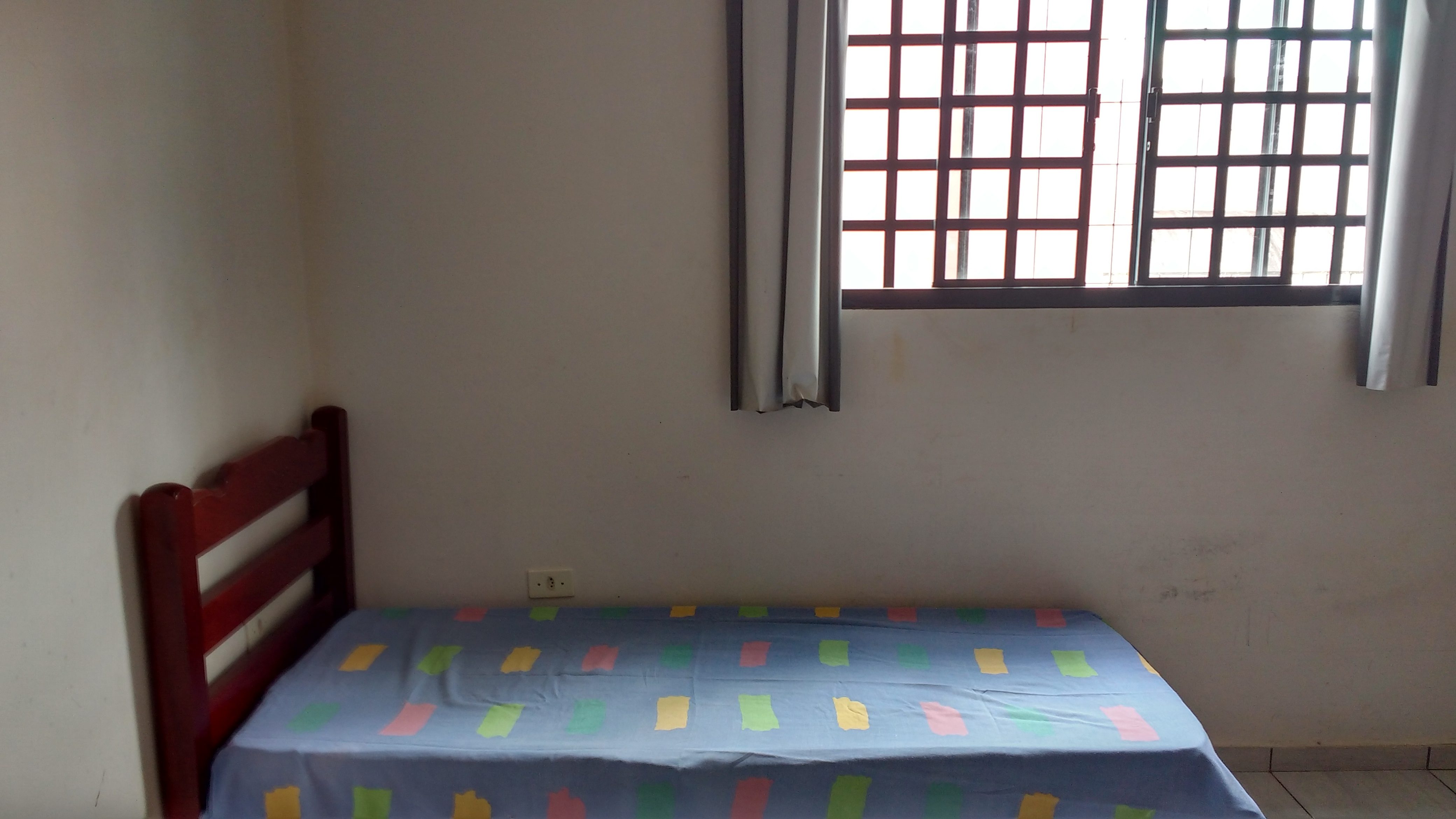 Quarto individual com cama junto à janela